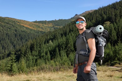 Man with backpack and sleeping mat in mountains. Space for text