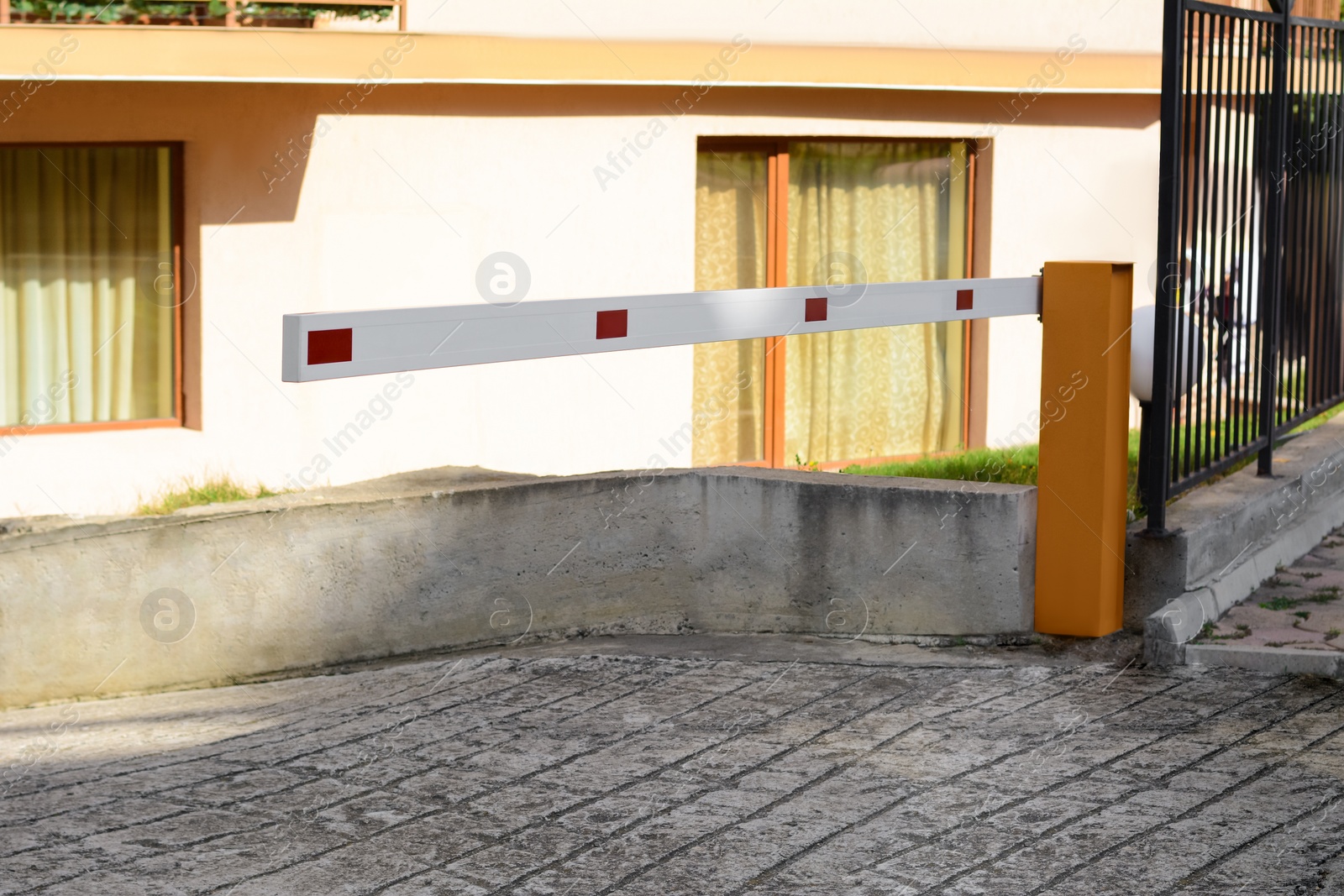 Photo of Closed boom barrier near building on sunny day