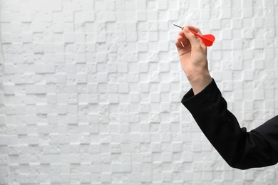 Photo of Woman holding dart against light wall. Business trainer concept