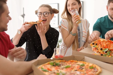 Young people having fun party with delicious pizza indoors