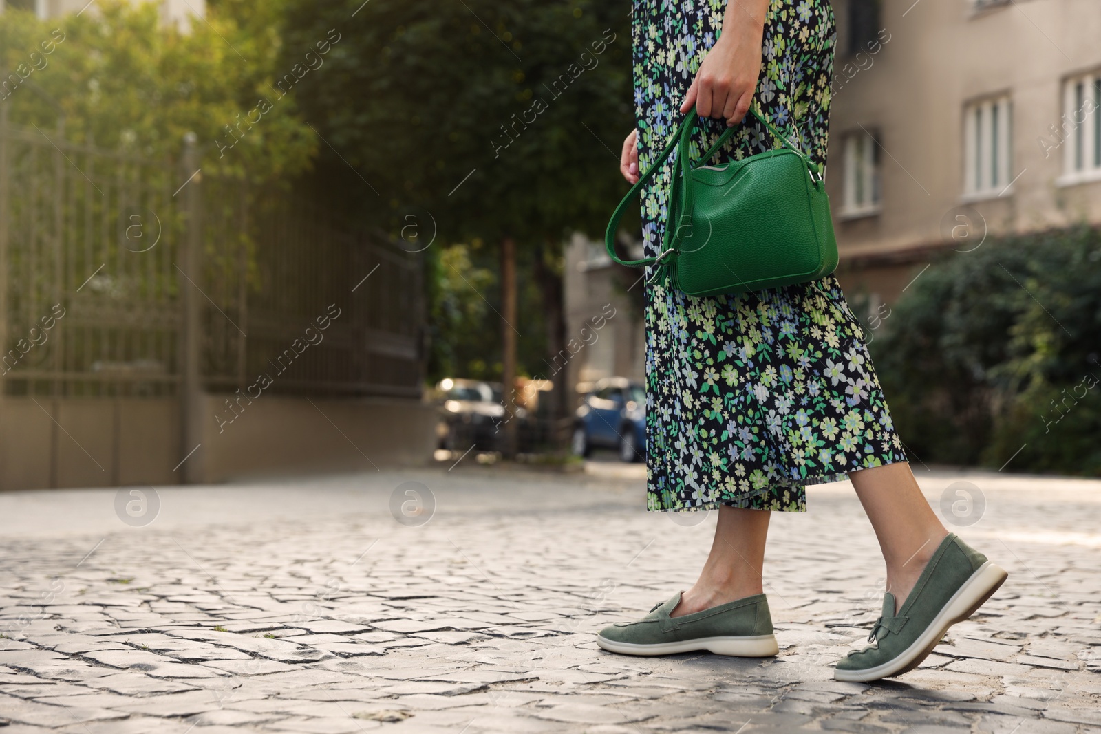 Photo of Woman with stylish green bag on city street, closeup. Space for text