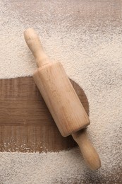 Imprint of board on wooden table with flour and rolling pin, top view