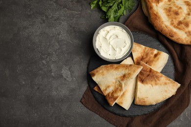 Photo of Cut pita bread, cream cheese and parsley on grey table, flat lay. Space for text