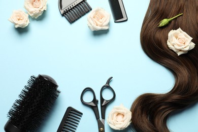 Flat lay composition with professional hairdresser tools, flowers and brown hair strand on light blue background. Space for text