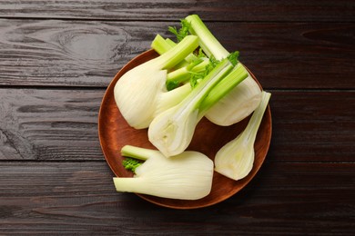Whole and cut fennel bulbs on wooden table, top view