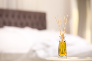 Reed air freshener with essential oil on table indoors. Space for text