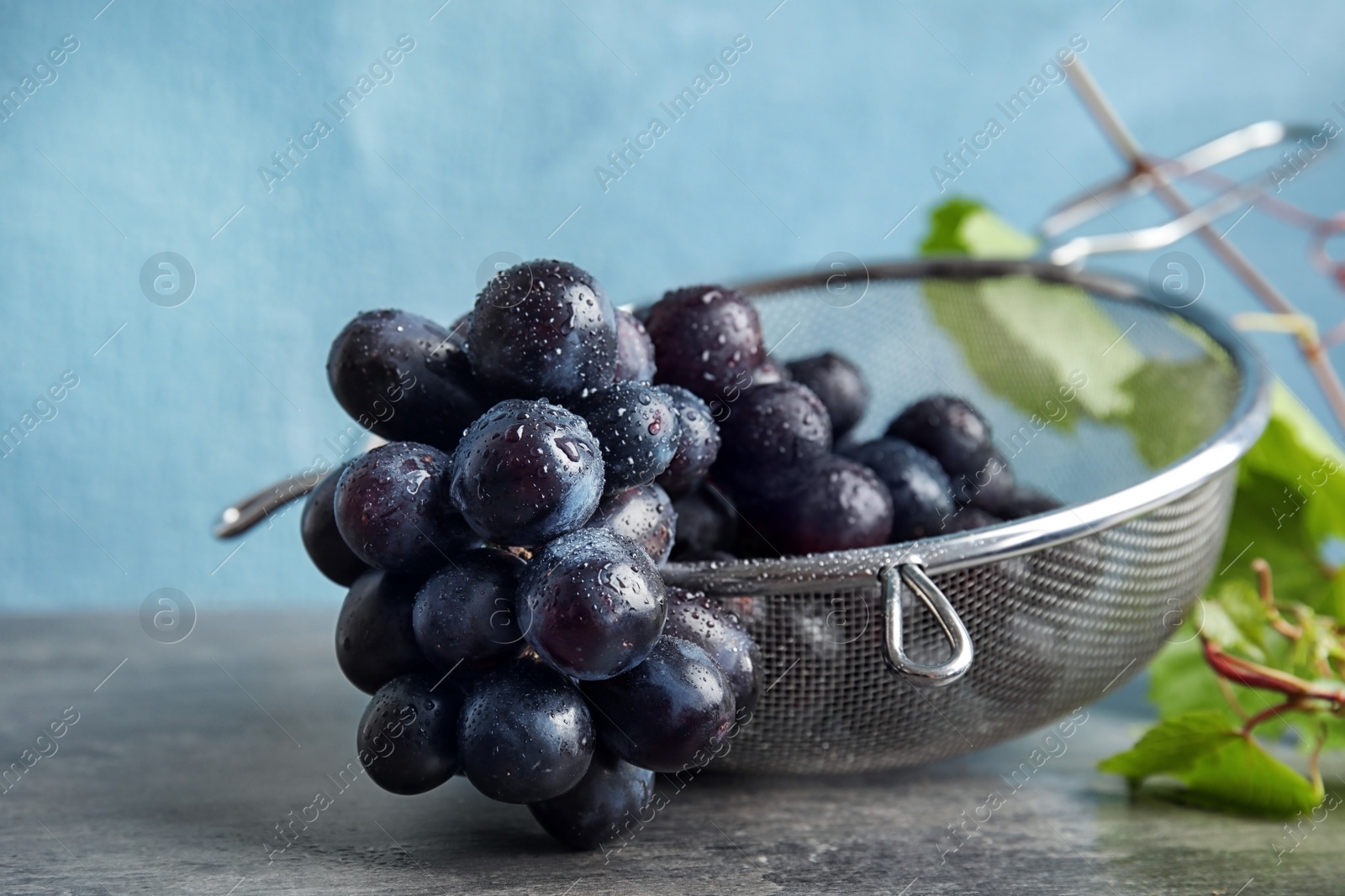 Photo of Fresh ripe juicy grapes in colander on table