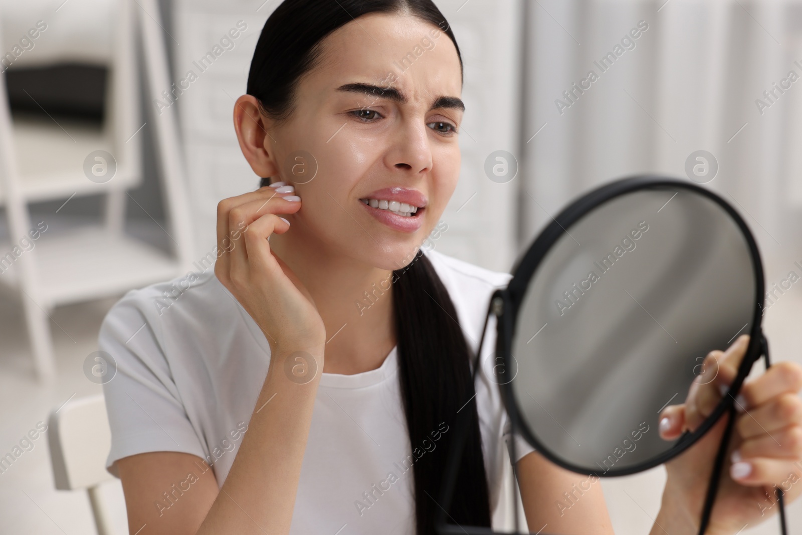 Photo of Woman with dry skin looking at mirror indoors