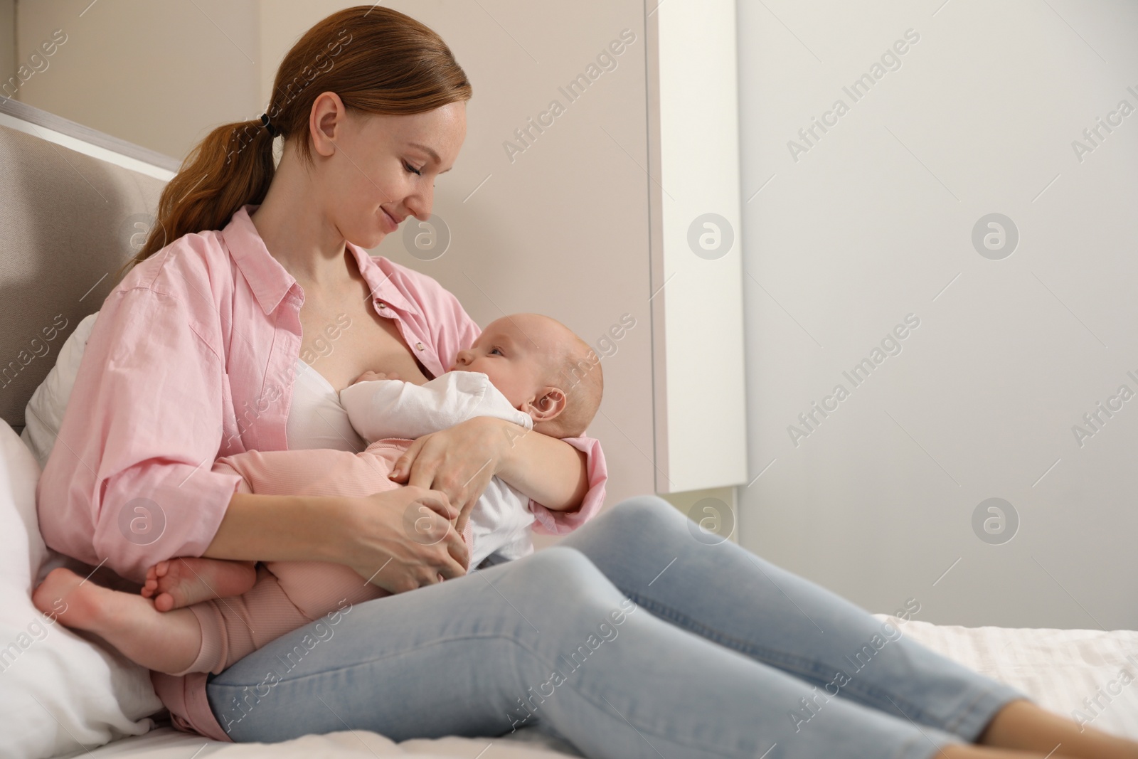 Photo of Young woman breast feeding her little baby in bedroom