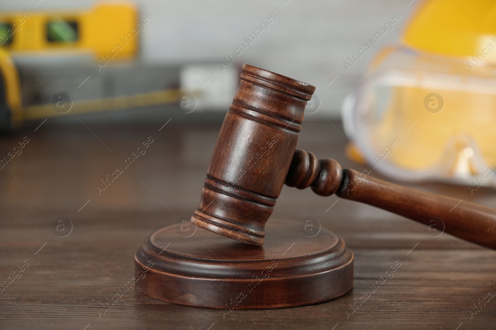 Photo of Construction and land law concepts. Judge gavel, protective helmet, safety glasses, ruler with level on wooden table