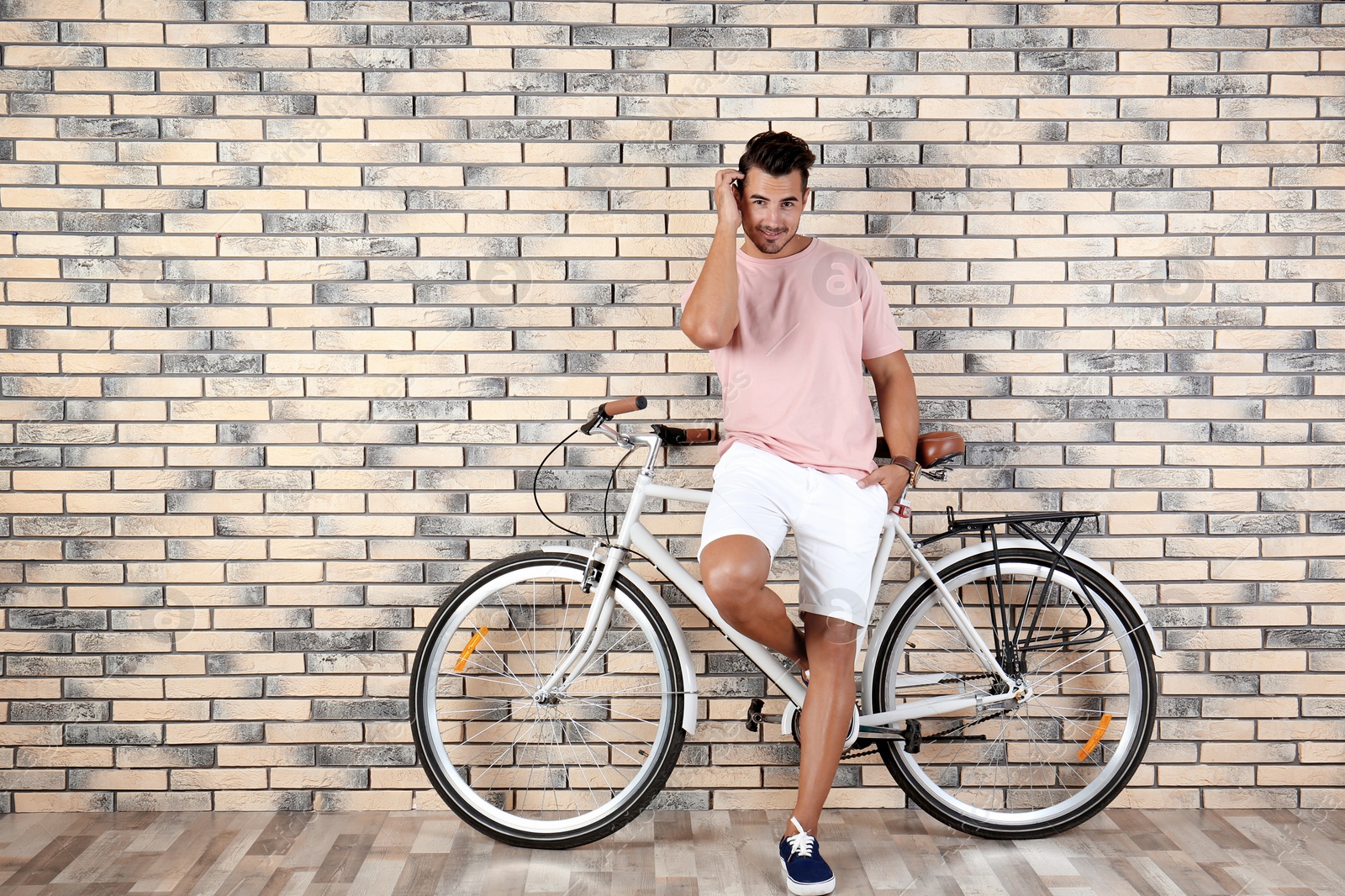 Photo of Handsome young hipster man with bicycle near brick wall