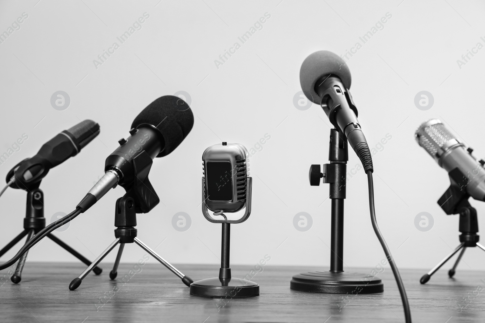 Image of Journalist's equipment. Different microphones on wooden table. Black and white effect