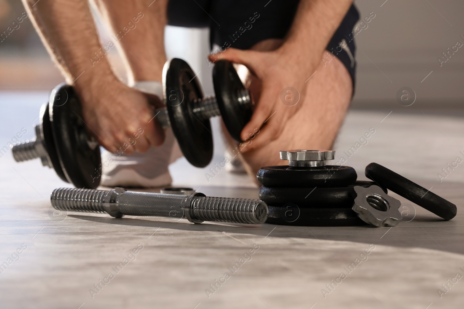 Photo of Male athlete with adjustable dumbbells indoors. Sports equipment