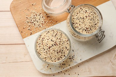 Photo of Bowl and jar with raw quinoa seeds on wooden table, top view