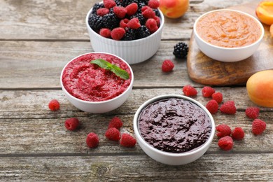 Photo of Different puree in bowls and fresh fruits on wooden table