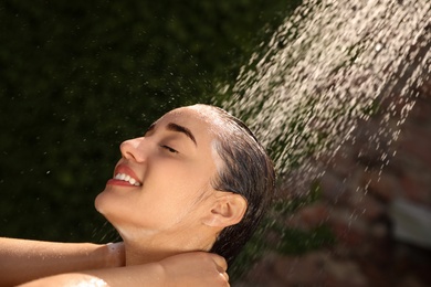 Photo of Woman washing hair in outdoor shower on summer day, closeup