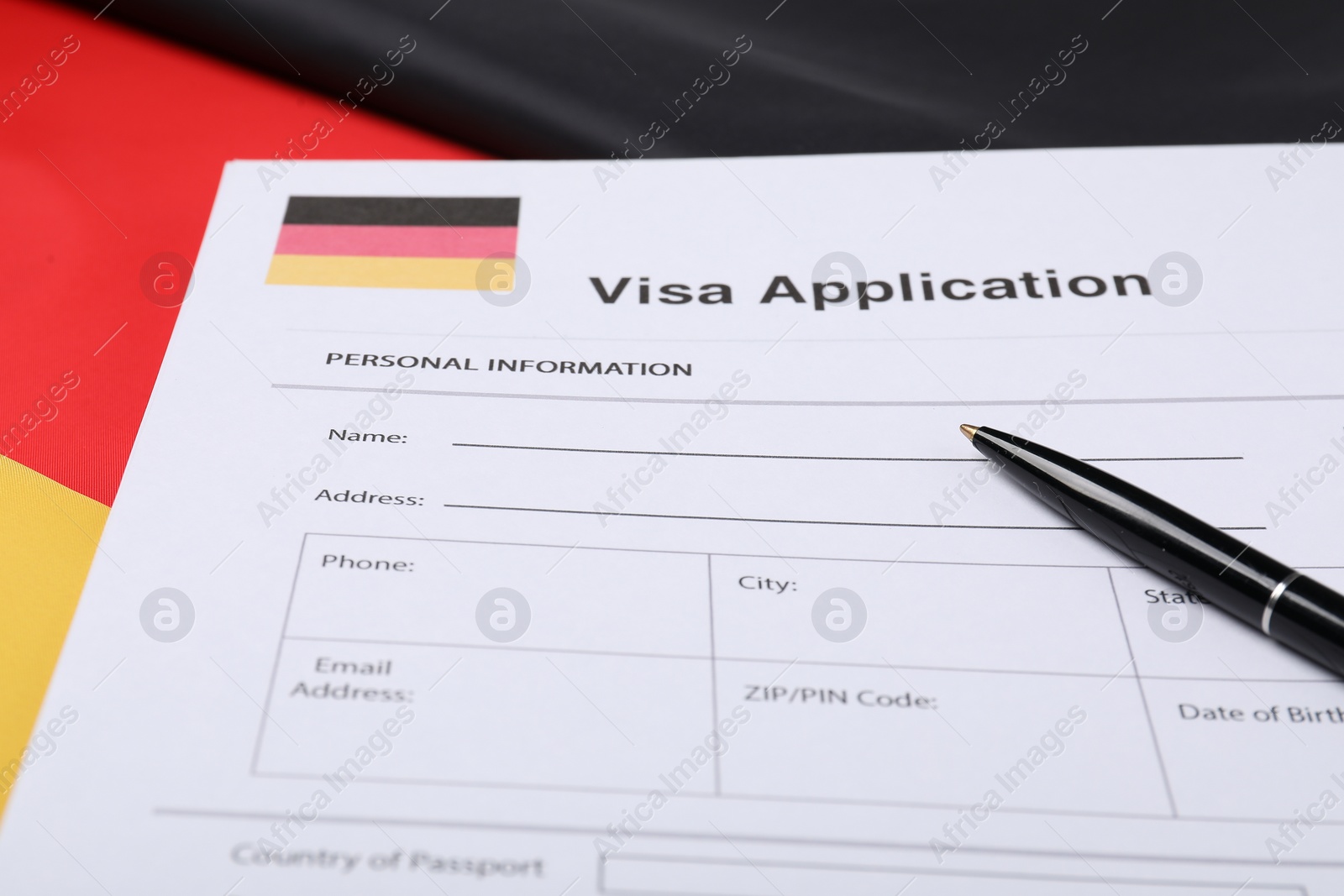 Photo of Immigration to Germany. Visa application form and pen on flag, closeup