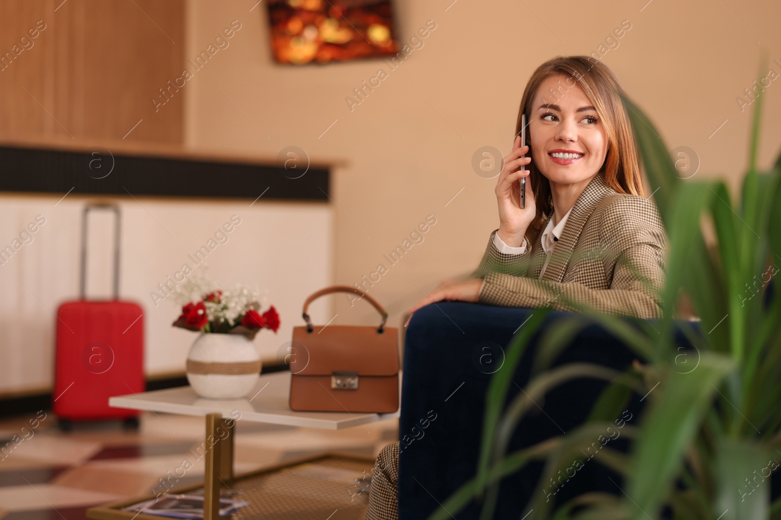 Photo of Beautiful woman talking on phone while waiting in hotel hall