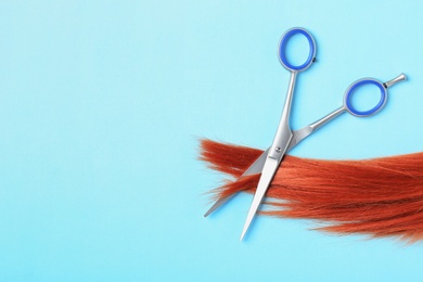 Flat lay composition with red hair, scissors and space for text on color background. Hairdresser service