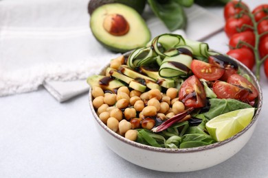 Photo of Delicious salad with chickpeas, vegetables and balsamic vinegar on white table, closeup. Space for text