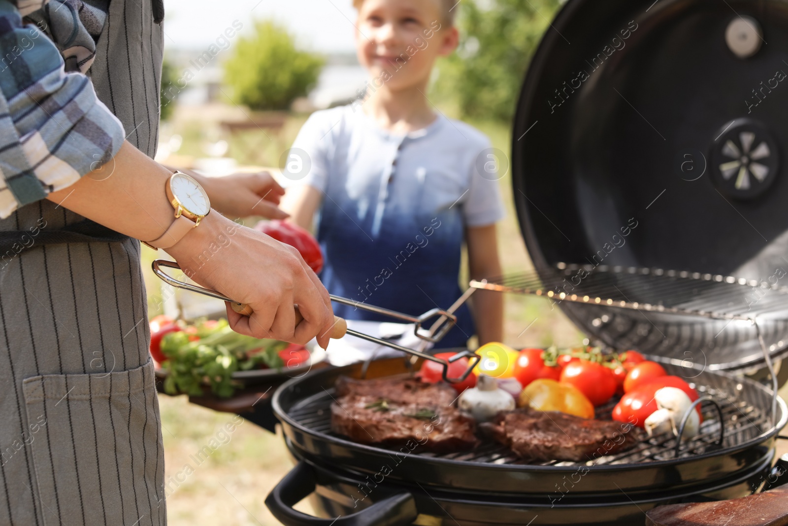 Photo of Happy family having barbecue with modern grill outdoors