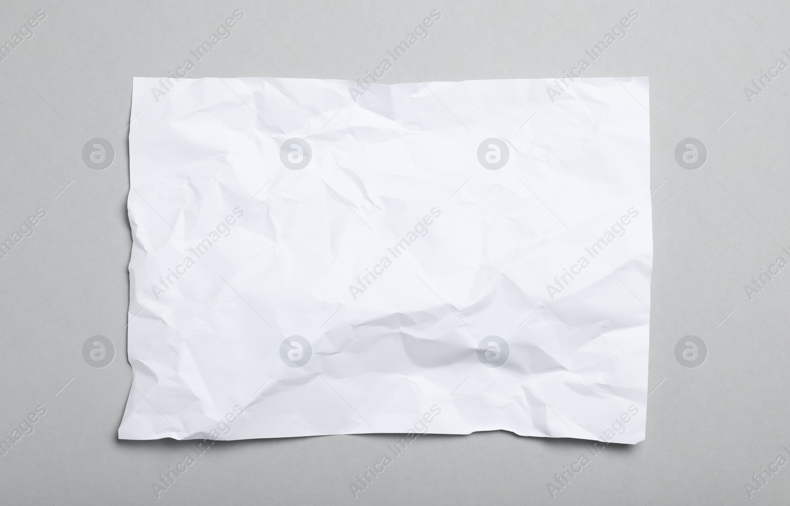 Photo of Sheet of white crumpled paper on grey background, top view