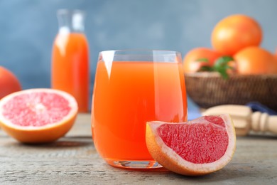 Tasty freshly made grapefruit juice and fruit on wooden table