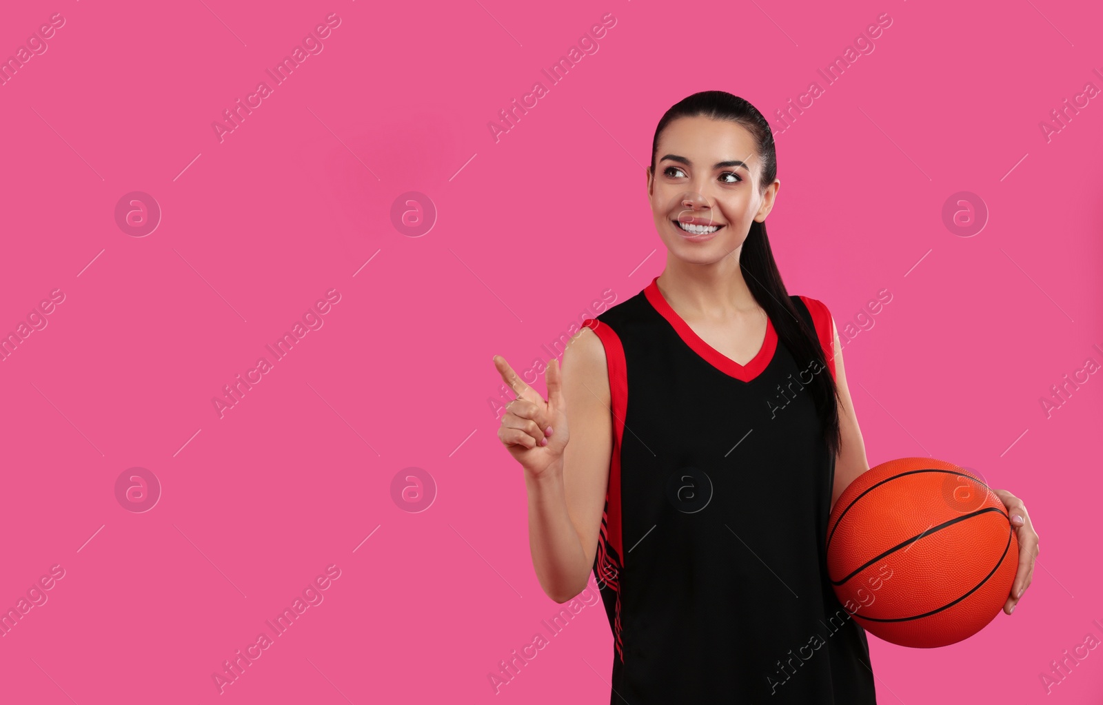 Photo of Basketball player with ball on pink background. Space for text