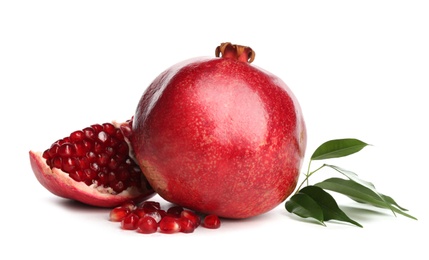 Ripe pomegranates with leaves on white background