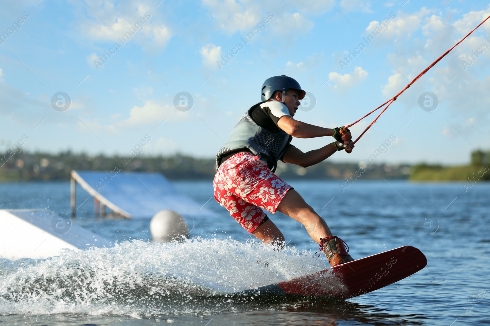 Photo of Teenage boy wakeboarding on river. Extreme water sport