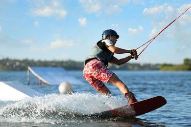 Photo of Teenage boy wakeboarding on river. Extreme water sport