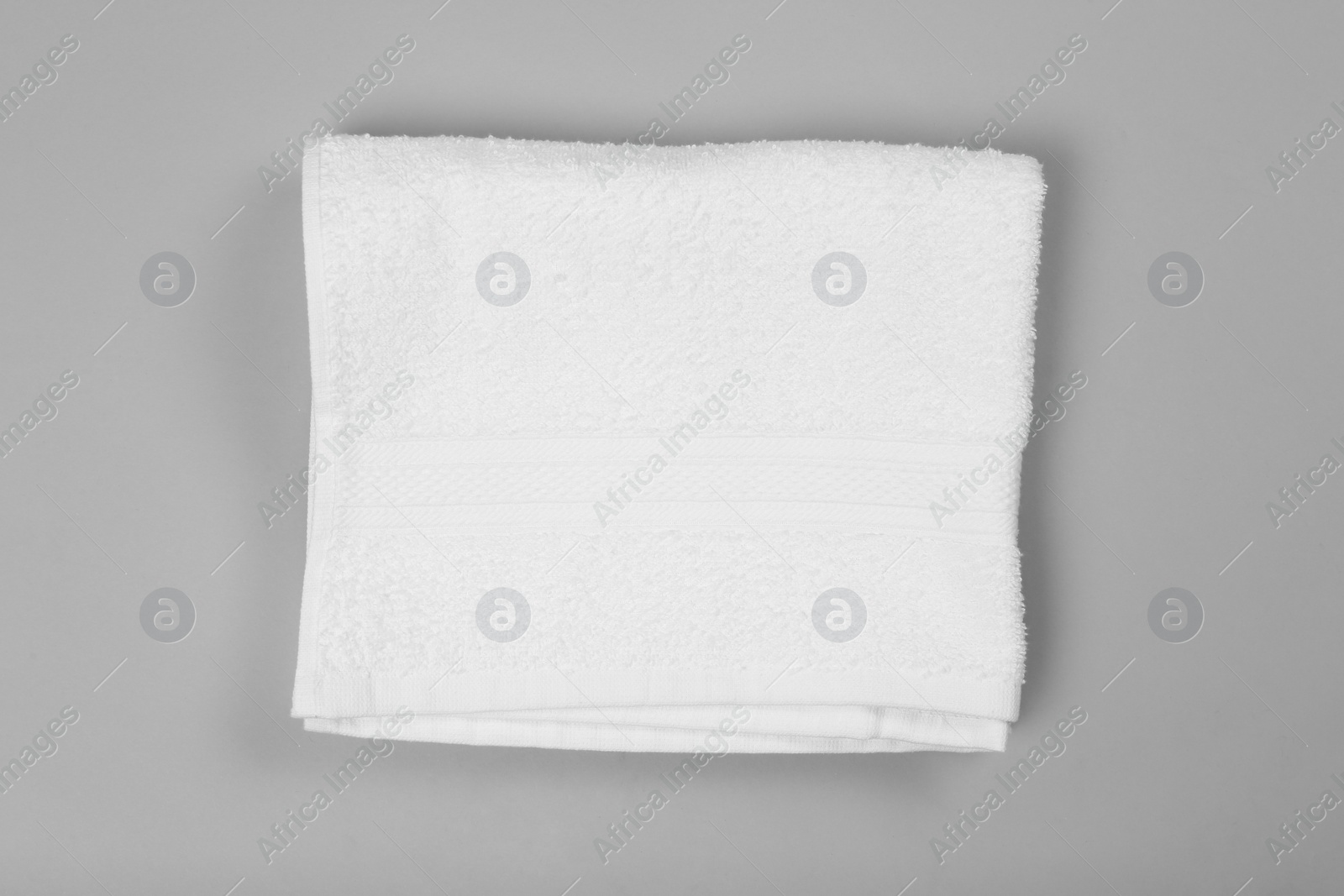 Photo of Folded white beach towel on light grey background, top view