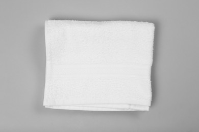 Folded white beach towel on light grey background, top view