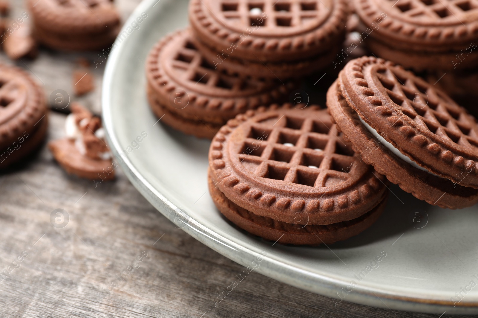 Photo of Tasty chocolate sandwich cookies with cream on wooden table, closeup