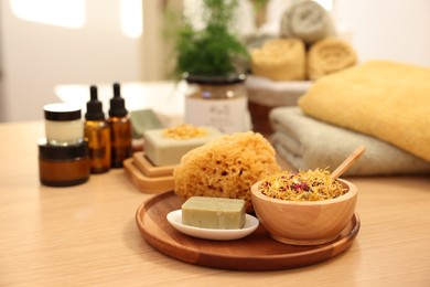 Photo of Dry flowers, loofah and soap bar on wooden table indoors. Spa time