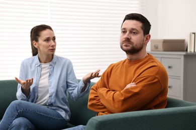 Photo of Offended husband ignoring his wife indoors. Relationship problems