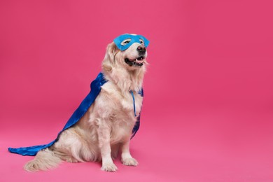 Photo of Adorable dog in blue superhero cape and mask on pink background, space for text