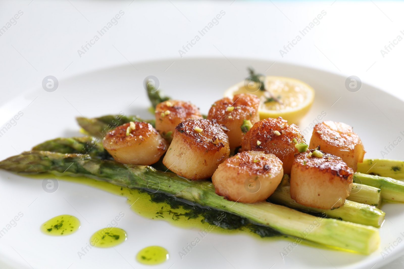 Photo of Delicious fried scallops with asparagus, lemon and thyme on white background, closeup