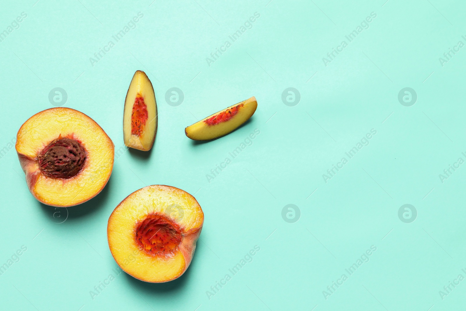 Photo of Cut and whole fresh ripe peaches on light blue background, flat lay. Space for text