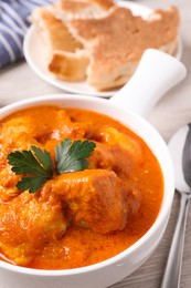 Bowl of delicious chicken curry on white wooden table, closeup