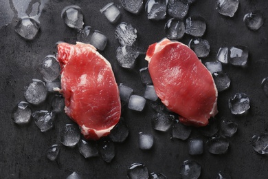 Flat lay composition with raw meat and ice cubes on dark background