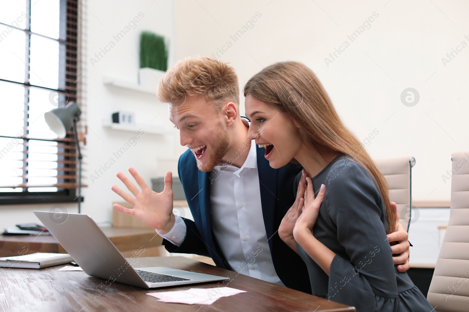Photo of Happy young people playing online lottery using laptop in office