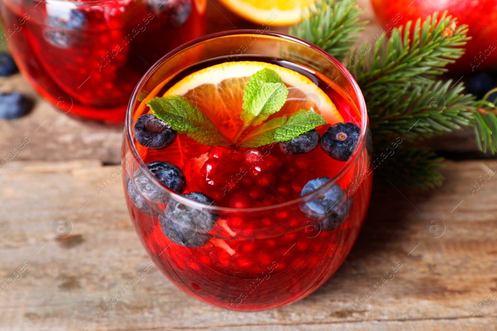 Photo of Aromatic Christmas Sangria drink in glasses on wooden table, closeup