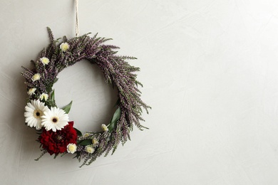 Photo of Beautiful autumnal wreath with heather flowers hanging on light grey background. Space for text