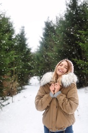 Young woman in snowy conifer forest. Winter vacation