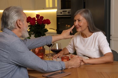 Photo of Affectionate senior couple having romantic dinner at home