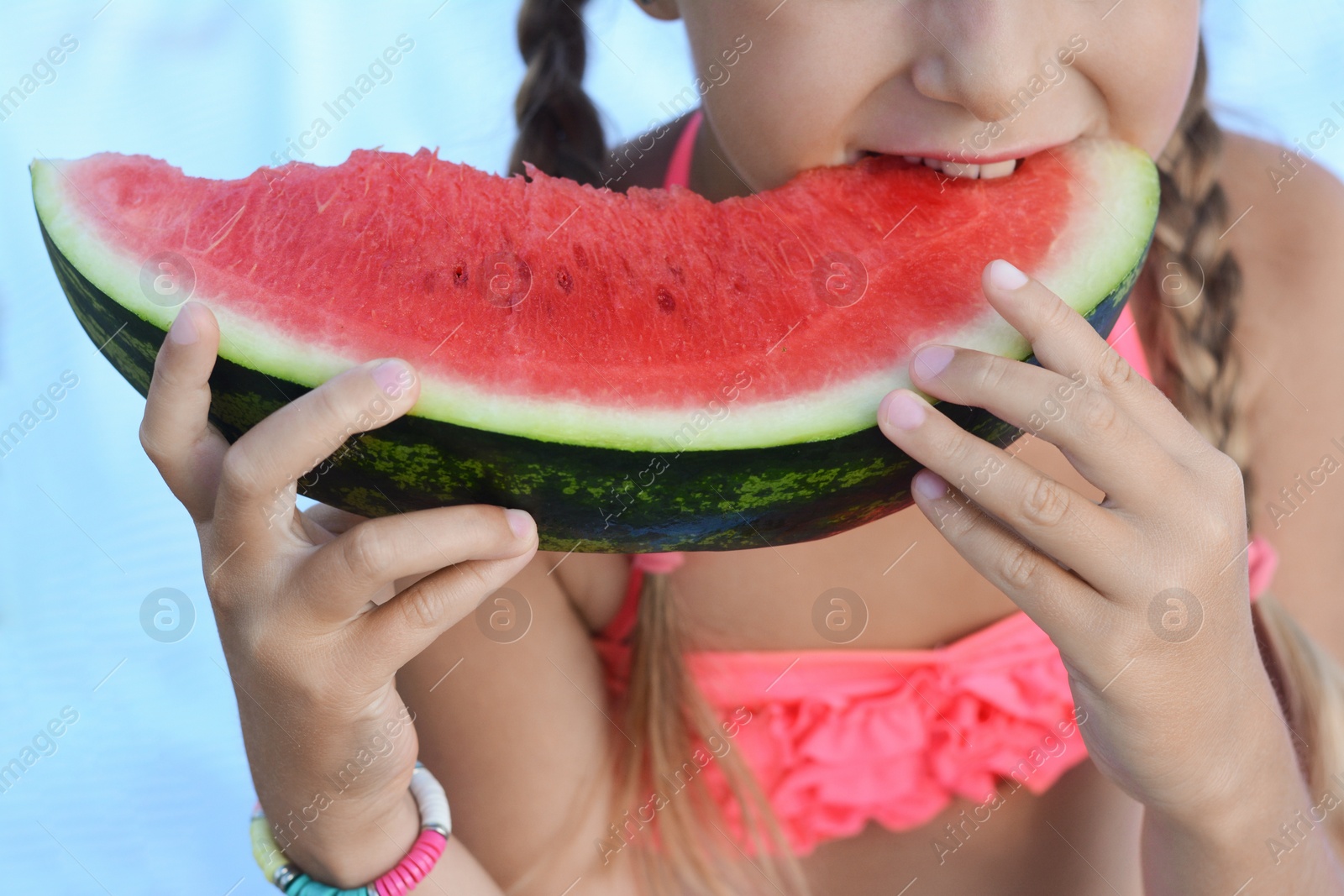 Photo of Little girl eating juicy watermelon on beach, closeup