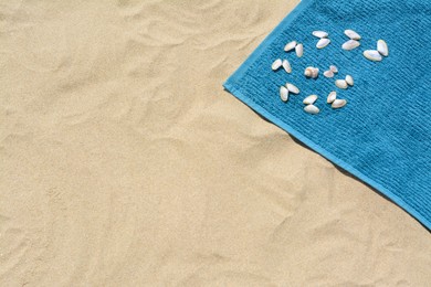 Towel and seashells on sand, above view with space for text. Beach accessory