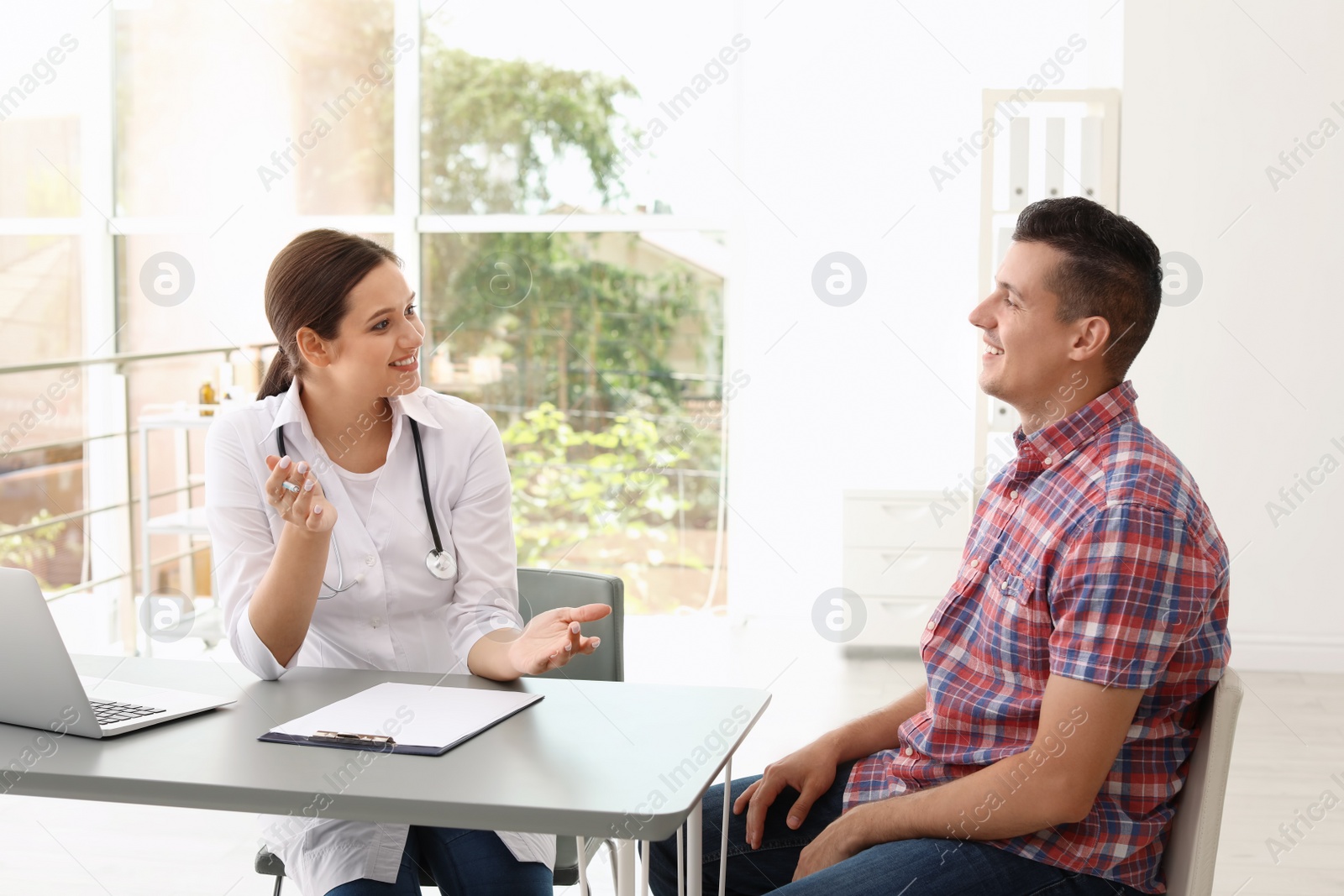 Photo of Young doctor speaking to patient in hospital