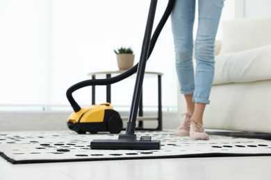 Photo of Young woman using vacuum cleaner at home, closeup